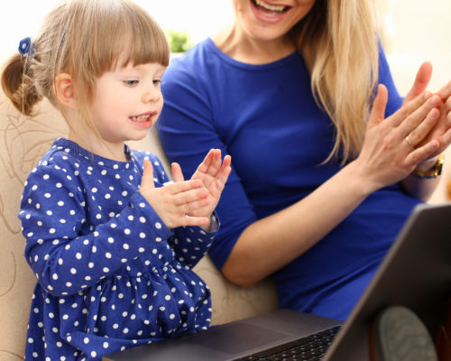 Cute little girl on couch with mom use laptop Cute little girl on couch with mom use laptop pc for chat with her dad away on business portrait. Point finger hand in display social web network bank mortgage credit wireless ip telephony concept